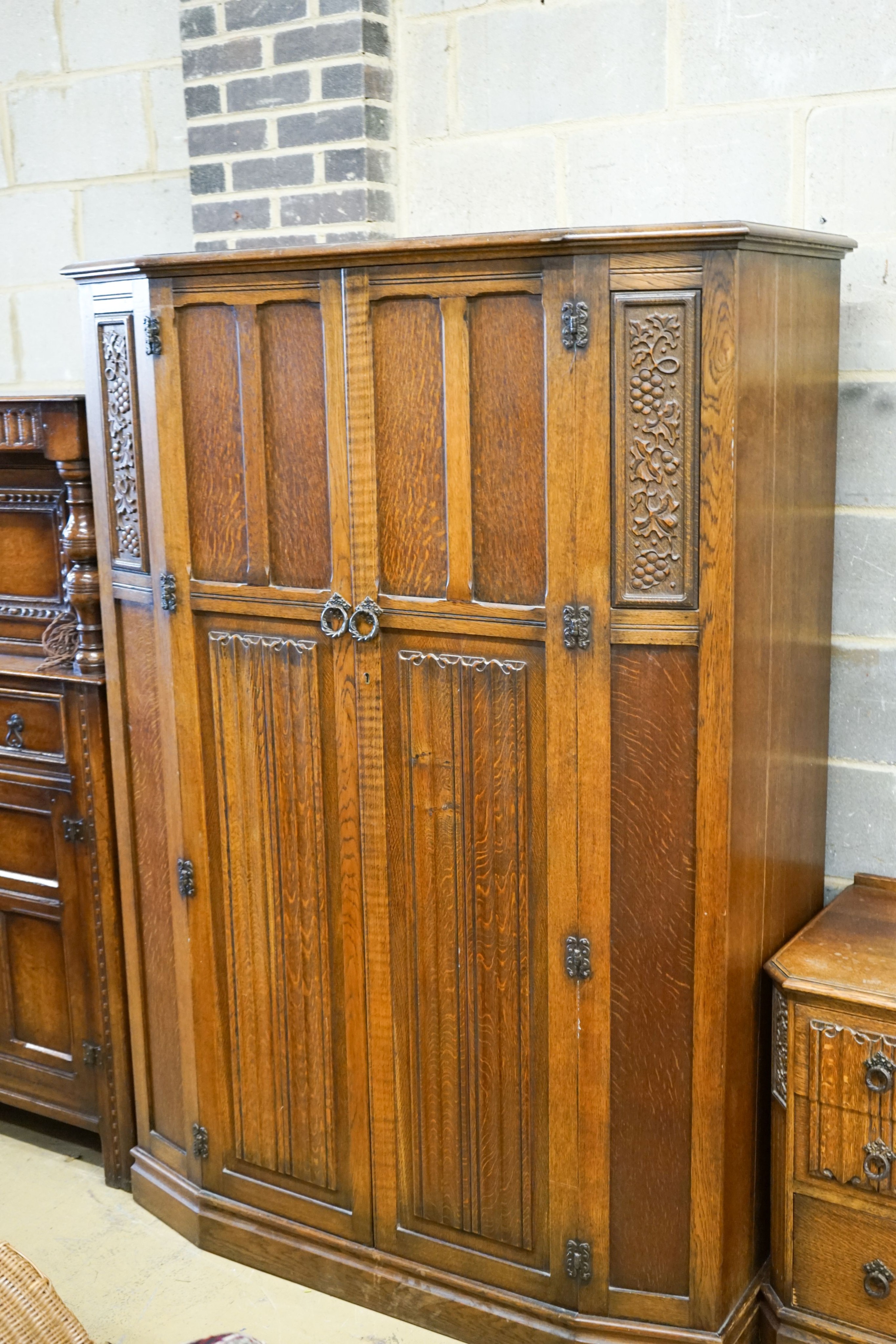 An early 20th century Jacobean revival linenfold moulded oak three piece bedroom suite, larger wardrobe length 128cm, depth 58cm, height 183cm